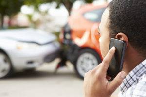 A man on his cell phone at the scene of a car accident