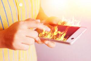 hands holding cell phone on fire