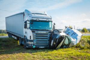 A small motor vehicle being crushed after colliding with a big truck.