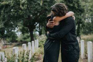 grieving couple hugging at a gravesite