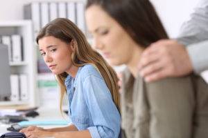 woman uncomfortable to see her manager grabbing her co-worker’s shoulders