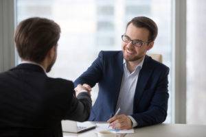 A client smiles as they shake hands with a lawyer.