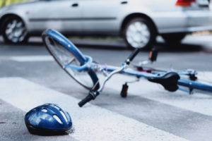 an overturned bicycle and a helmet in the middle of a crosswalk