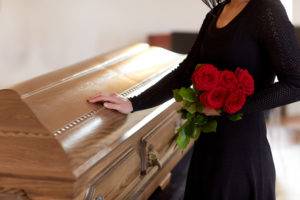 woman with flowers touches casket