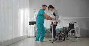 A doctor helps a patient with a severe injury learn to walk again. An Englewood catastrophic injury attorney can help recover medical bills and other damages.