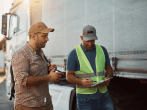 Men discussing paper work next to truck